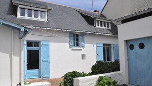 Un edificio blanco con contraventanas azules y un techo gris.