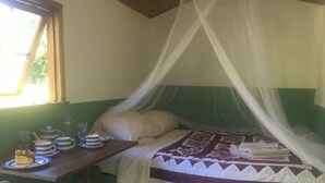 Una habitación con una cama bajo un dosel, una mesa con juego de té y una silla.