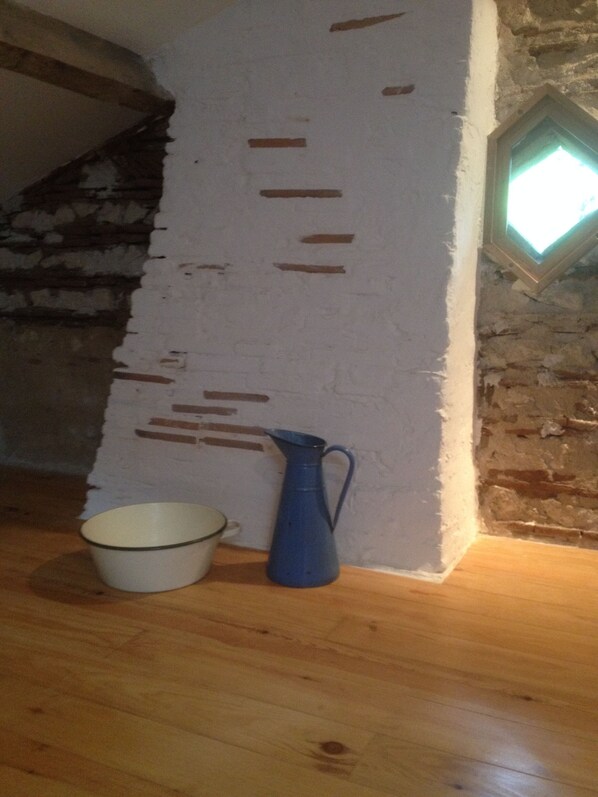 A room with exposed brick walls, a wooden floor, a white bucket, and a blue pitcher. - Country retreat in the midst of Dordogne's vineyards (Gardonne)