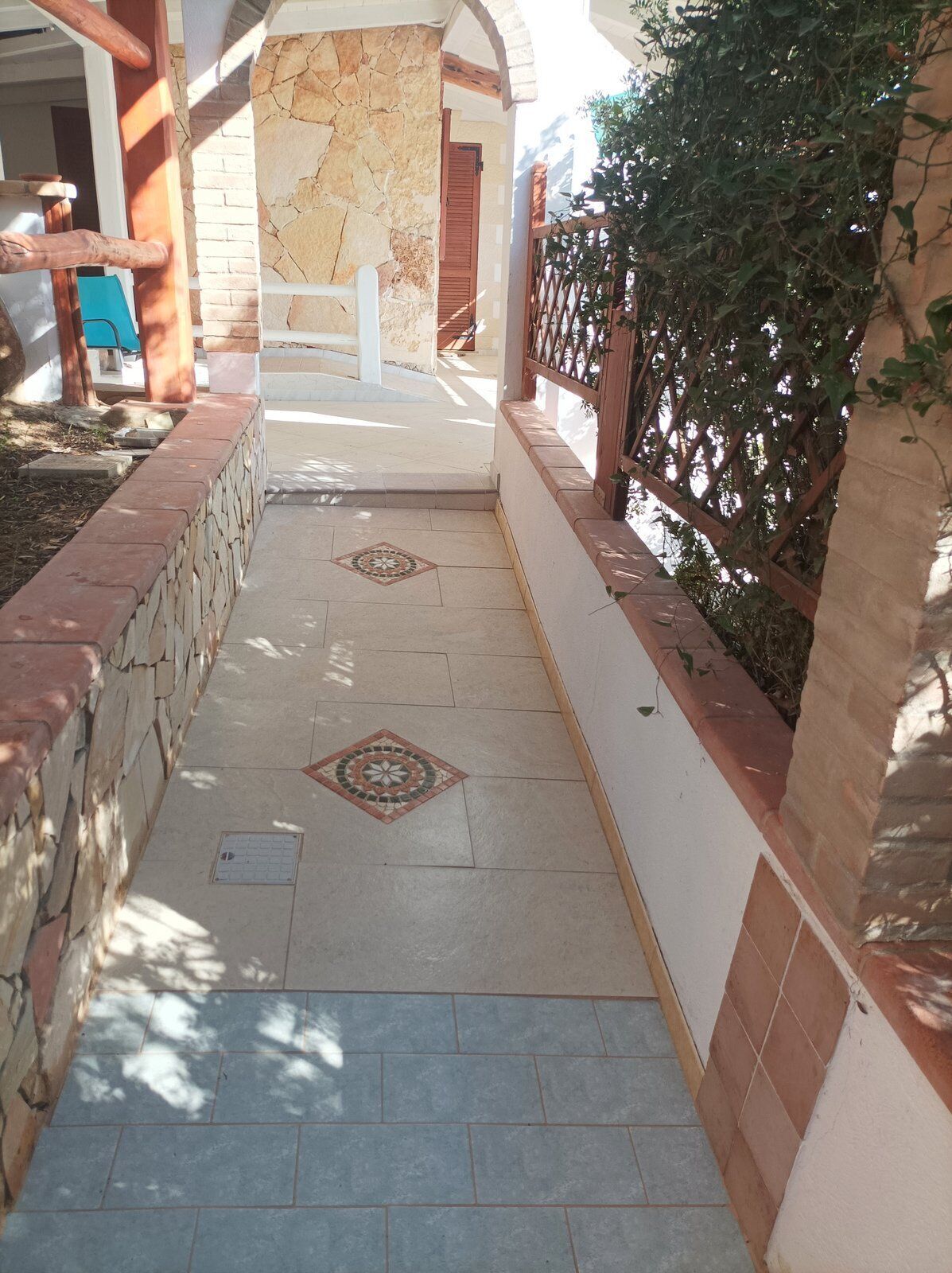 A corridor with stone walls, tiled flooring, and a metal gate.