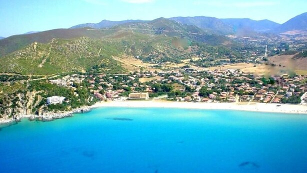 A coastal town with a beach, buildings, and mountains in the background. - Comfortable apartment with terrace overlooking the sea, near Villasimius (Solanas)