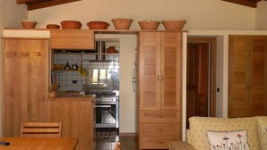 Een keuken met houten kastjes, een fornuis en een eethoek met een tafel en stoelen.