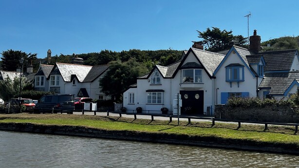 A row of white houses with blue trim and steep roofs, situated along a canal. - Breakwater Cottage - Five Bedroom Cottage, Sleeps 10 (Bude)