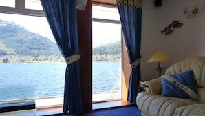 A room with a large window, a sofa, and a lamp. - Waterfront with Private Hot Tub, Kayaks and Paddleboards free for guests use !!! (ARROCHAR)