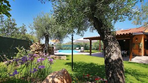 Un jardin avec une piscine, une pergola et un mur en pierre.