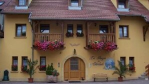A yellow building with a wooden door, two balconies with flower boxes, and a bench outside. - apartment/ flat - Soultzmatt (Soultzmatt)