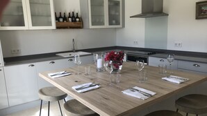 Una cocina moderna con una isla de madera, taburetes de bar, botellas de vino en la pared y un florero con flores.