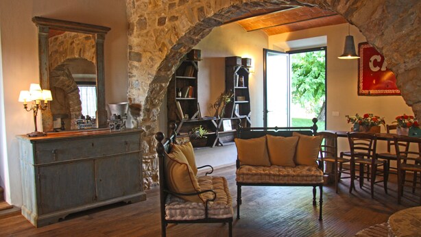 A rustic interior with stone walls, a wooden bench, a sofa, and a dining area.
