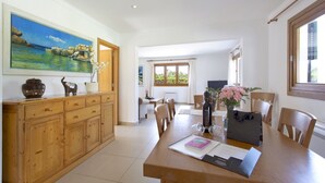 A spacious dining area with a wooden table, chairs, and a painting of a coastal scene on the wall. - Ca Na Volantina - Great family villa close to Puerto Pollensa (Port de Pollença)