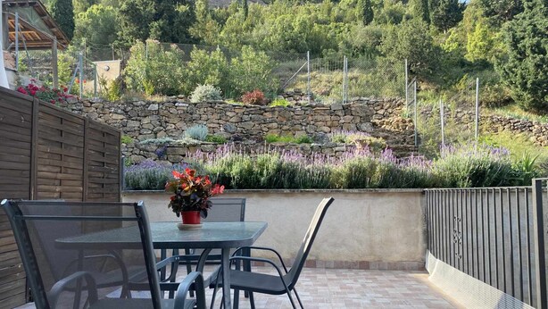 An outdoor patio with a stone wall, a metal table, and chairs. - Casa Lola Beceite Apartments, mountain views and petfriendly (Beceite)