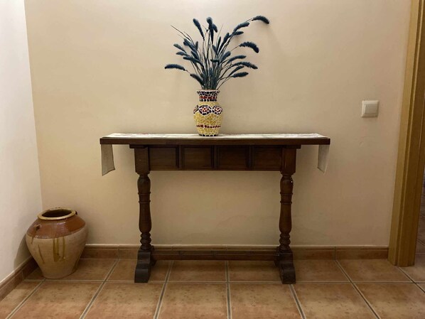 Um console de madeira com um vaso em mosaico e uma planta decorativa.