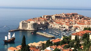A coastal town with historic buildings, a harbor with boats, and a prominent castle-like structure. - Studio Apartment Klara  Breathtaking view to the sea and Old Town! (Dubrovnik)