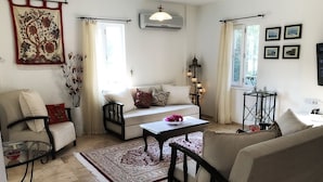 A living room with a sofa, armchairs, a coffee table, a rug, and a hanging tapestry.