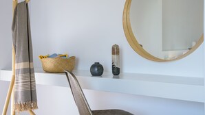 A room with a white wall, a round mirror, a woven basket, and a black vase. - Summer Breeze! Airy, spacious and fully equipped sea view apartment. (Ag. Nikolaos)