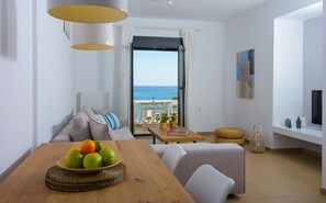 Relax in this serene space with a view of the sea, featuring a comfortable sofa, dining table, and large window.