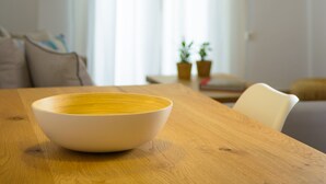 A dining table with a white bowl, a wooden table, and a hanging light fixture. - Summer Breeze! Airy, spacious and fully equipped sea view apartment. (Ag. Nikolaos)