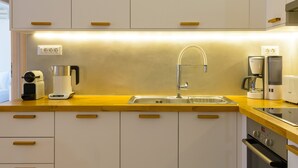 A modern kitchen with white cabinets, wooden countertops, a stainless steel sink, and built-in appliances including a coffee maker and a toaster. - Summer Breeze! Airy, spacious and fully equipped sea view apartment. (Ag. Nikolaos)