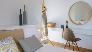 A modern hotel room with a bed, a desk, a chair, a mirror, and decorative items. - Summer Breeze! Airy, spacious and fully equipped sea view apartment. (Ag. Nikolaos)