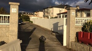 Una calle residencial con casas numeradas 83 y 82, un acceso vehicular con portón y un automóvil estacionado al fondo.