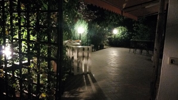 An outdoor area with a paved walkway, a gated entrance, and a street lamp.