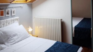 Ein Schlafzimmer mit einem Bett, einem Nachttisch, einem Spiegel und einer Heizung.