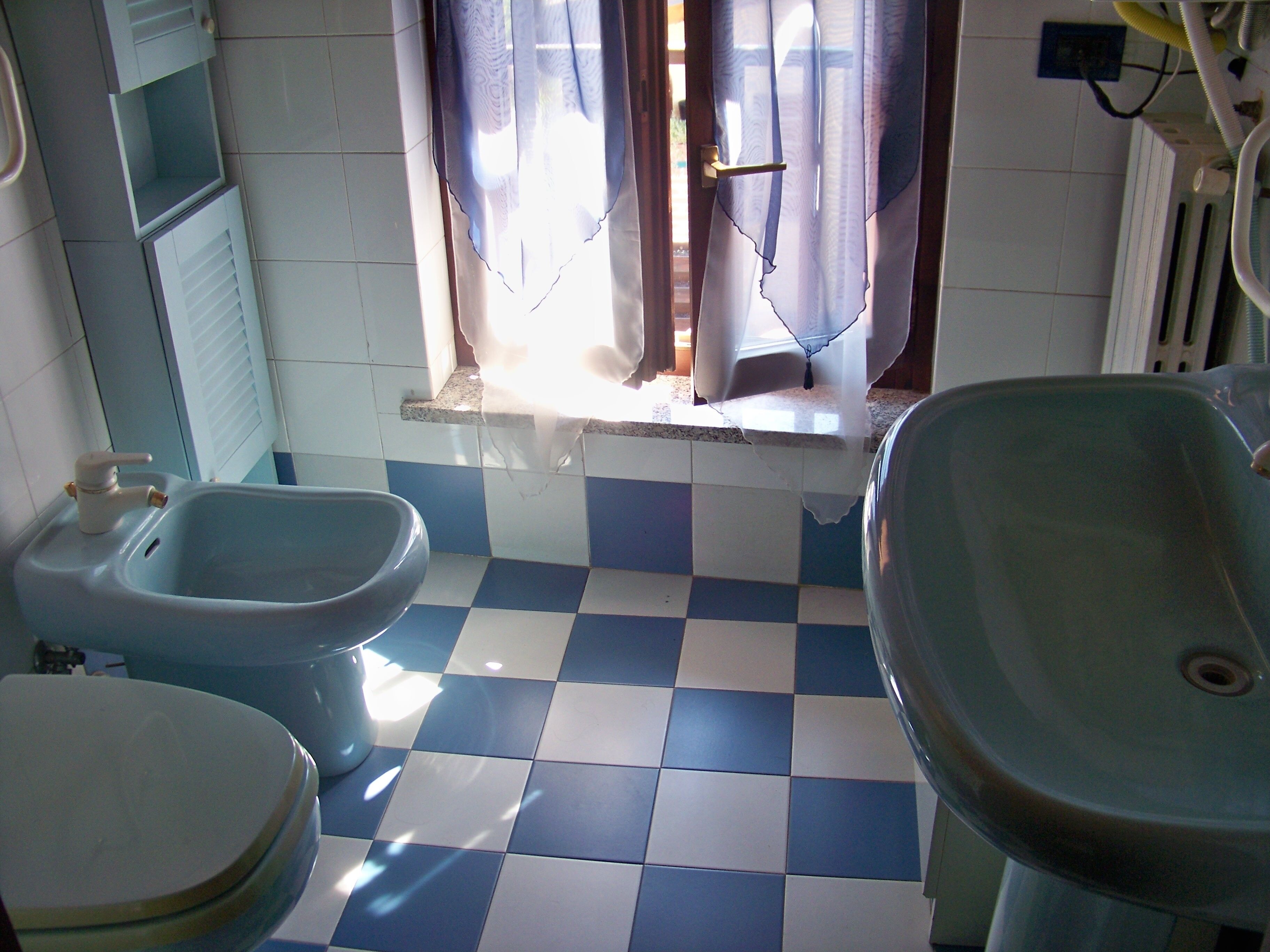 Een badkamer met een zwart-witte vloertegel, een wastafel, een toiletbril en een toilet.