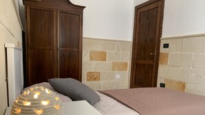 A bedroom with a bed, a nightstand, a lamp, and wooden doors.