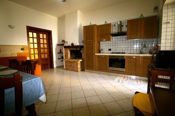 A kitchen with wooden cabinets, a tiled backsplash, and a dining area with a table and chairs. - Otranto holiday home with three bedrooms and only a two minute walk to the beach (Otranto)