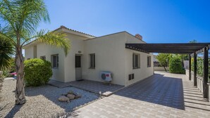 A two-story house with a covered patio, a palm tree, and a small garden area. - 'The Winning Post' - 3 Bed, 2 Bath, Single Storey Villa with Private Pool in Sea Caves (Peyia)