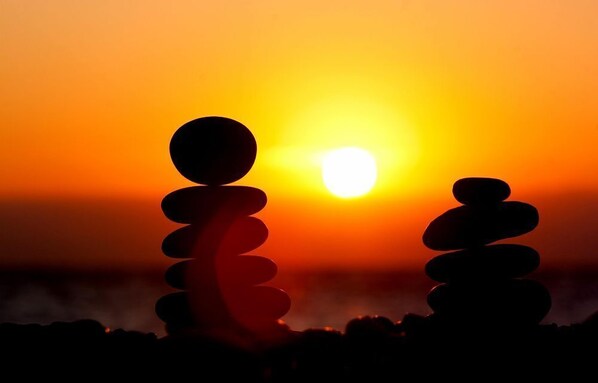 A sunset with a silhouette of stacked stones against the sky.