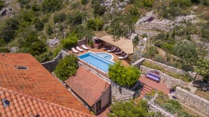 Una piscina en la azotea con un muro de piedra, sillas de descanso y un banco de piedra.