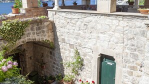 Un edificio de piedra con techo de tejas, una pequeña escalera y plantas en macetas.