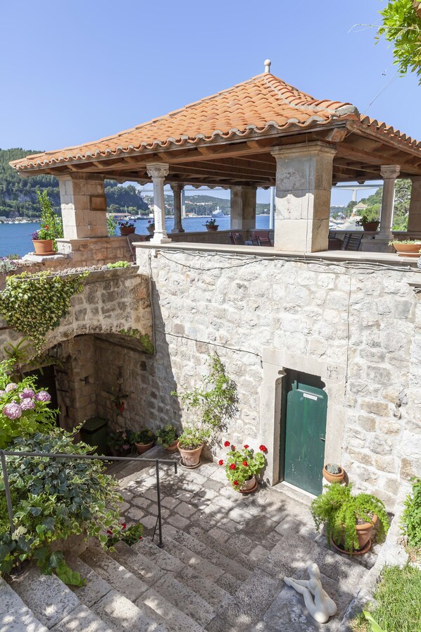 A stone building with a tiled roof, a small staircase, and potted plants.