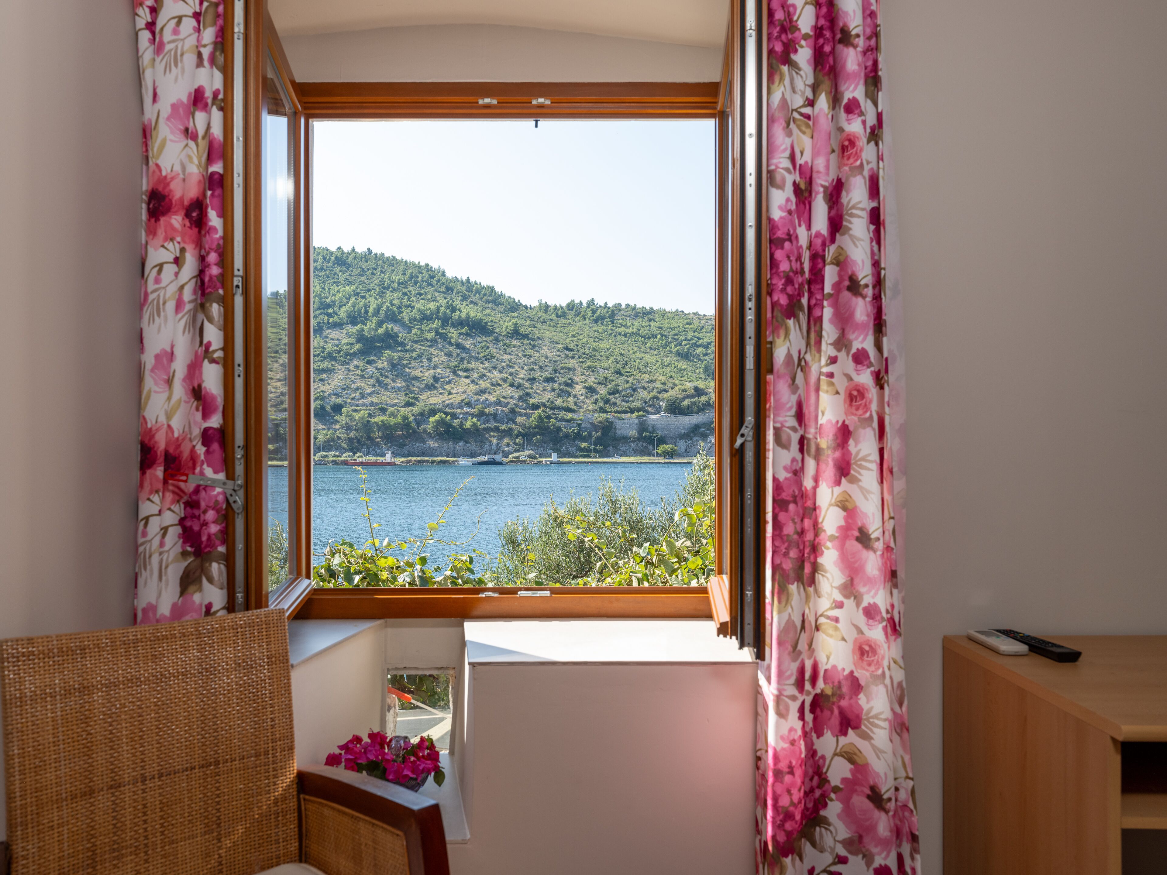 A room with a window overlooking a lake and hills.