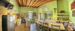 A kitchen with a wooden ceiling, a dining area with a table and chairs, and a green wall with religious artwork.
