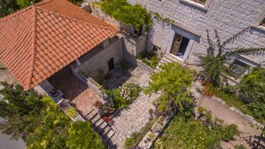 An aerial view of a courtyard with a red-tiled roof building, stone walls, and various potted plants.