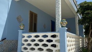 A building with a blue and white tiled facade, a white balcony with a lattice design, and potted plants in front. - Villa Fascinosa with sea / island currents view (portopalo di capo passero)