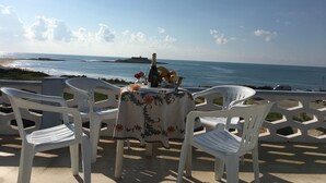 A table with a floral tablecloth, a bottle, and fruits, overlooking a beach with the ocean and a distant island. - Villa Fascinosa with sea / island currents view (portopalo di capo passero)