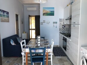A compact living space with a dining area, kitchenette, and a sofa.