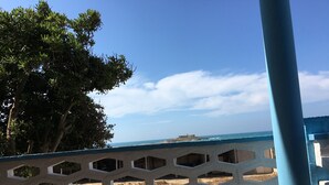A coastal view with a blue railing, a sandy beach, and a distant fortification. - Villa Fascinosa with sea / island currents view (portopalo di capo passero)