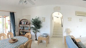 Un vaste salon comprenant un coin repas, une cheminée et un escalier menant à l’étage supérieur.
