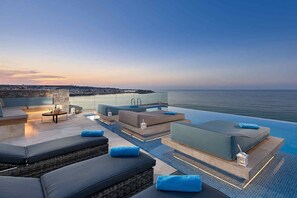 An infinity pool with a view of the sea, outdoor seating, and a glass railing. - Seafront Apt,central & quiet, infinity  pool next to the sea (Limenas Chersonisou)