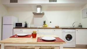 Een kleine keuken met een magnetron, broodrooster en wasmachine.