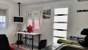 Una cucina moderna con zona pranzo, una TV sopra il bancone e una finestra con persiane.
