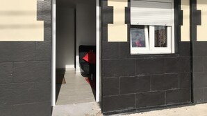 Un ingresso che dà su una stanza con una finestra, un oggetto rosso sullo sfondo e un lampadario sopra la porta.