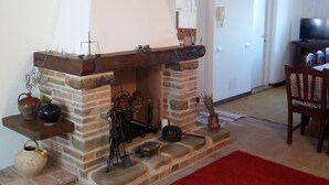 Una chimenea de piedra con repisa de madera, rodeada de diversos objetos decorativos y un tapete rojo.