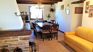 Un comedor con mesa y sillas de madera, una araña y un sofá amarillo.