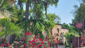 Un patio con un edificio de ladrillo, flores rojas y un letrero que dice 'Casale San Martino'.