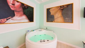 A bathroom with a white bathtub, two framed paintings on the wall, and a small shelf with toiletries. - Apartment in the historic center of Perugia (Perugia)