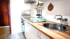 A kitchen with white cabinets, a stainless steel sink, wooden countertops, and a built-in range hood. - Apart. RIVERA II, location in Old town and only 10 minutes the beach. (Alicante)